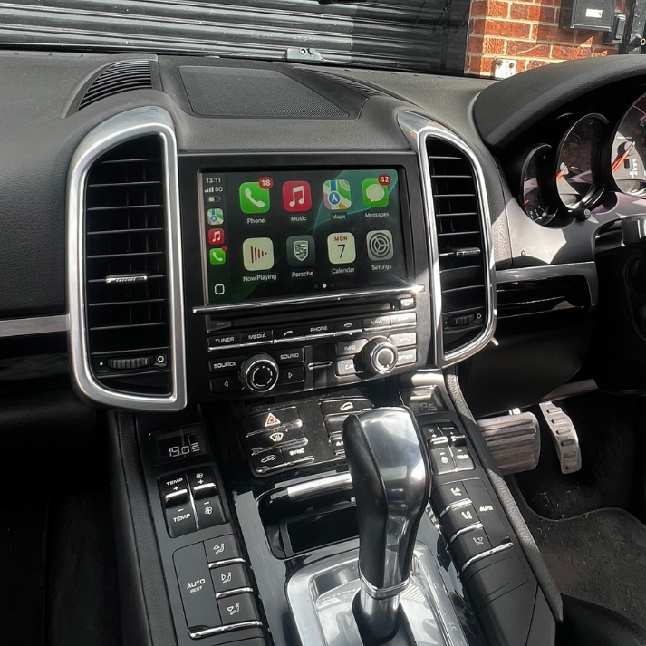 Car dashboard with a touchscreen display showing app icons. Apple CarPlay / Android Auto